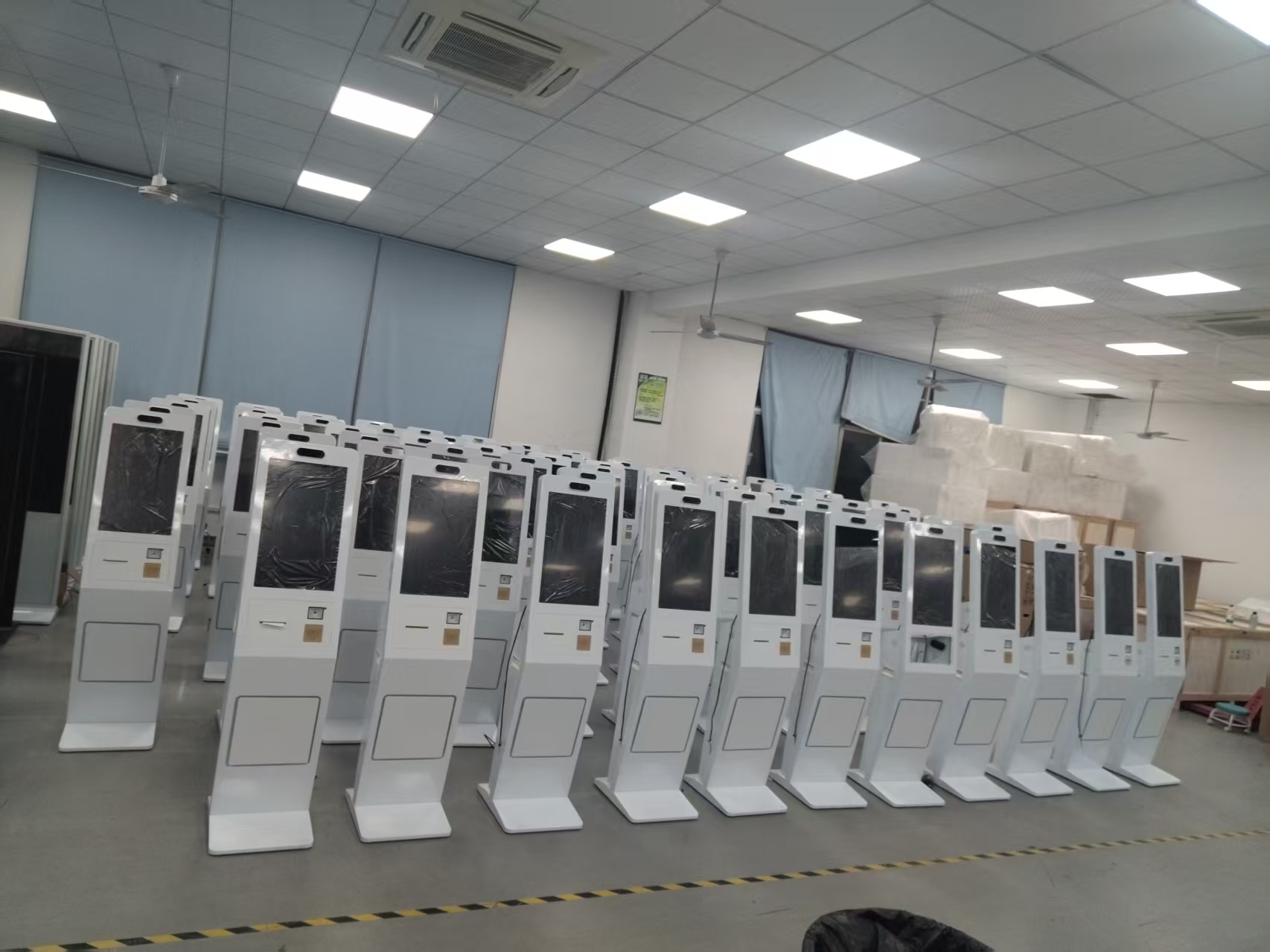 Rows of white self-service ordering kiosks in a production workshop