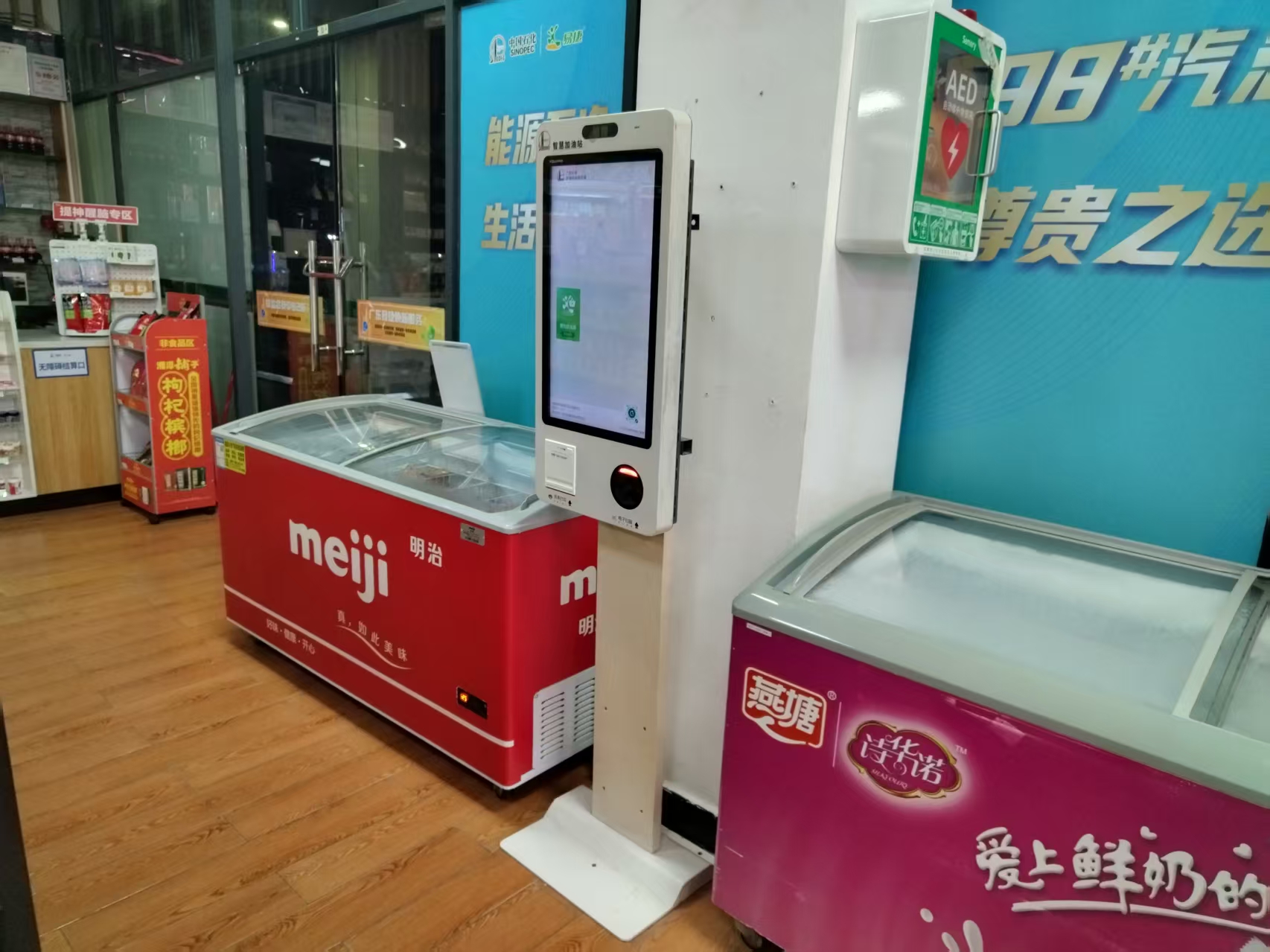 Self-service ordering kiosk installed beside freezer cases in a convenience store