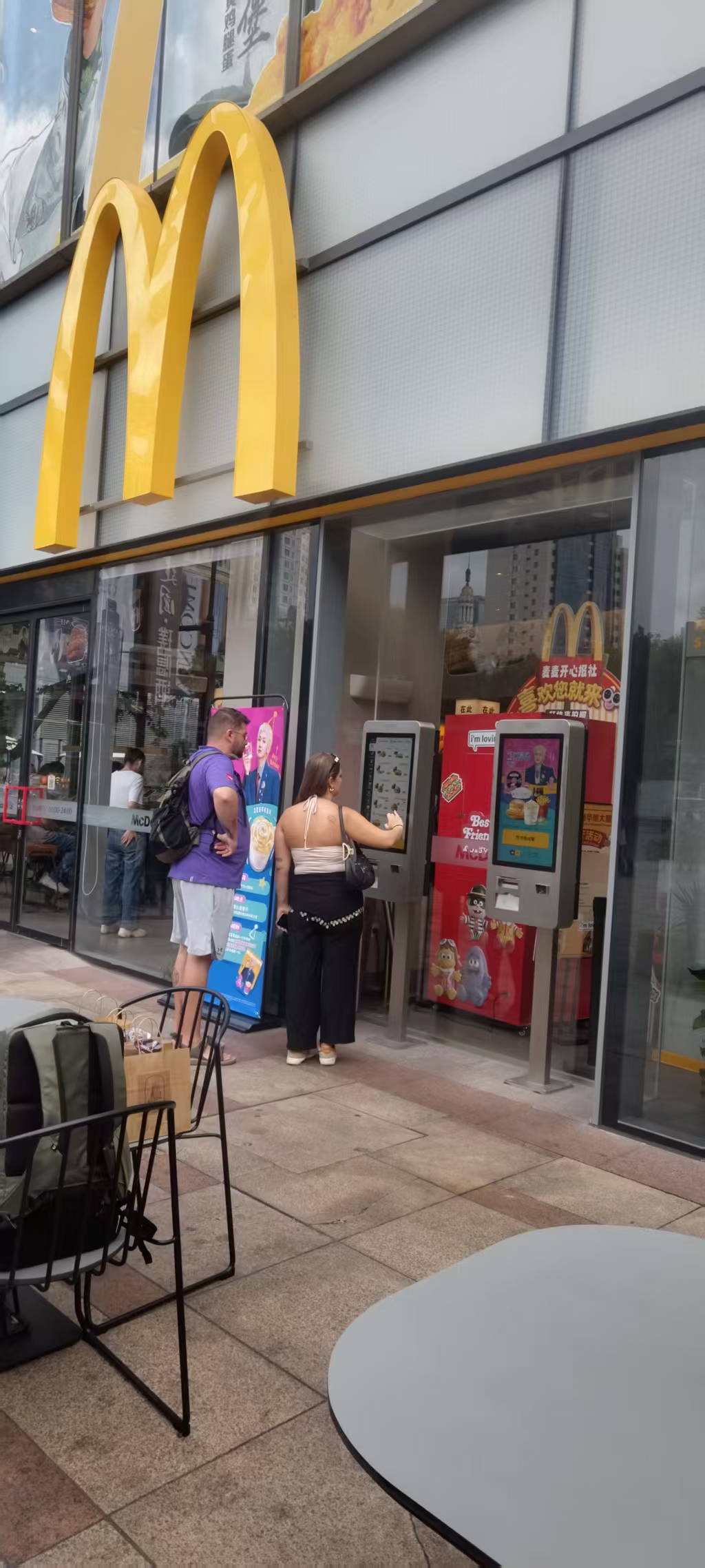Customers using self-ordering kiosks outside a quick-service restaurant