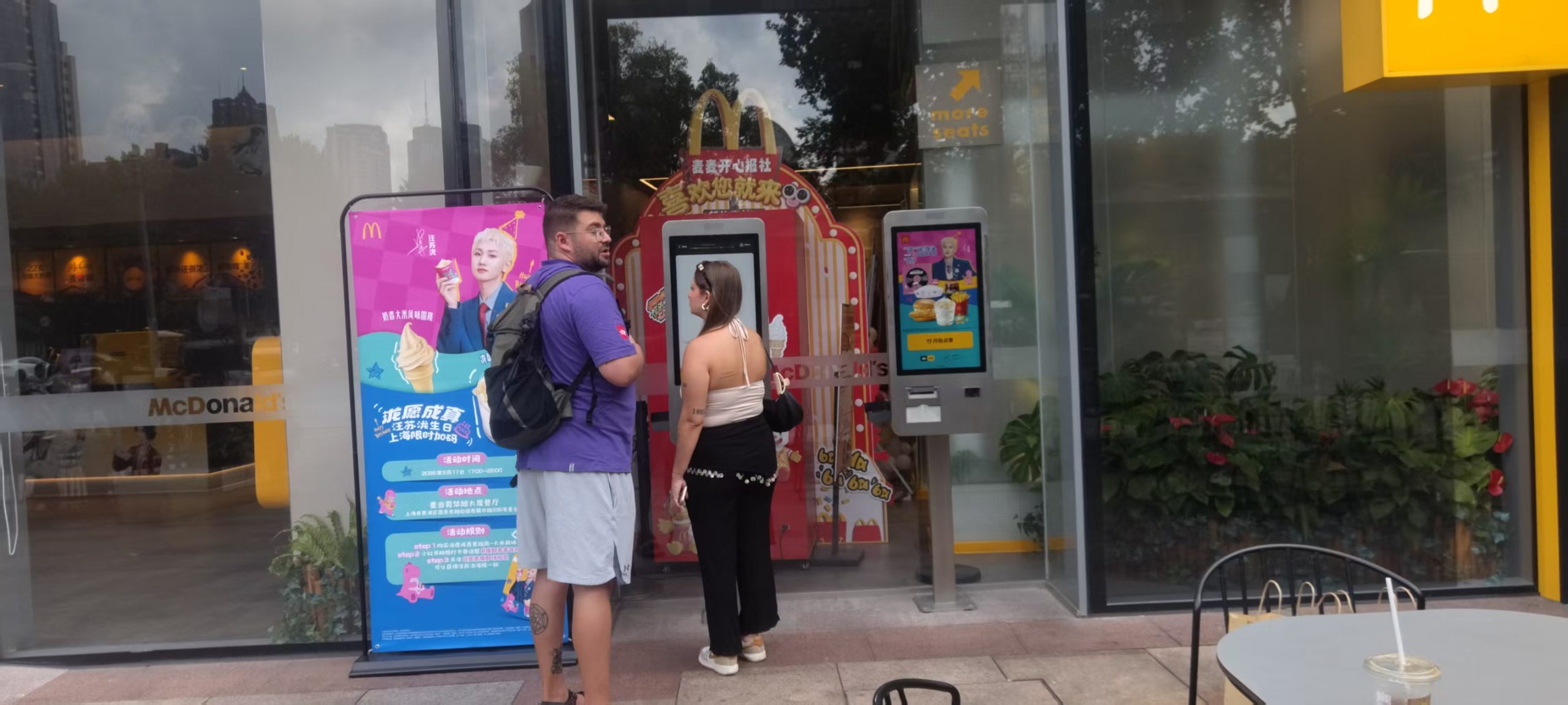Customers standing beside a restaurant self-ordering kiosk at the storefront
