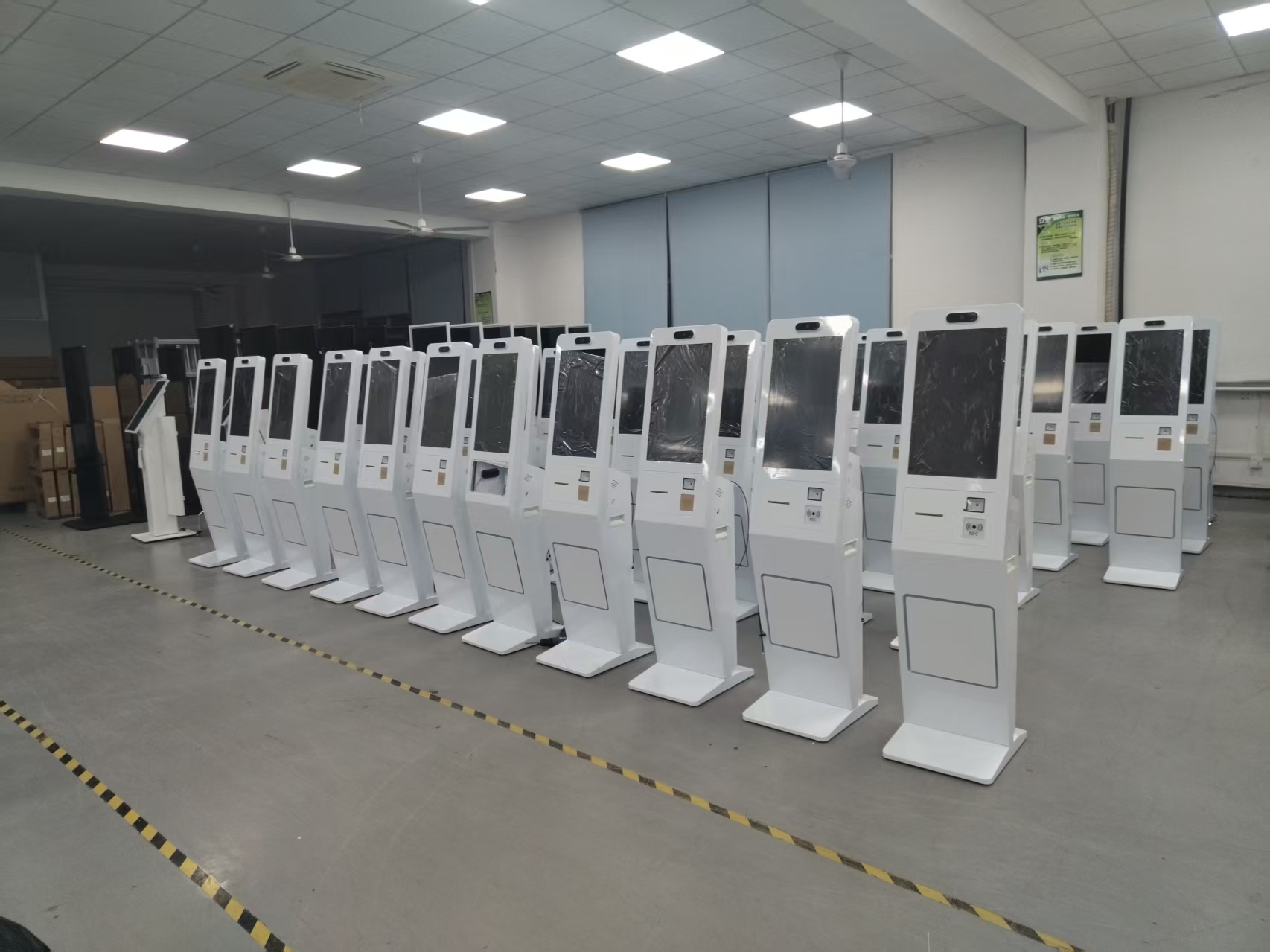 White self-service kiosks lined up in a workshop inspection area
